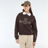 Buzo de felpa color marrón con cuello polo blanco en contraste. Presenta un estampado gráfico frontal con estilo universitario que incluye la inscripción 'Wellington Florida' y un emblema central.