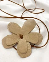 Gargantilla con dije de flor de cuero color beige y tiento de cuero marrón.