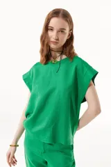 Blusa verde de lino con calce recto, cuello a la base y hombros caídos.