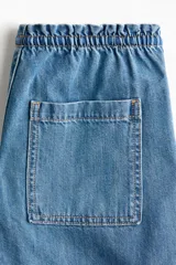 Pantalón de jean de corte holgado y pernera recta, color celeste con efecto deslavado. Cuenta con cintura elástica fruncida y cordón ajustable.