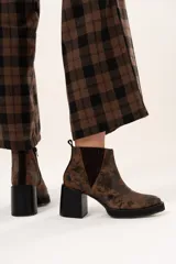 Bota tipo chelsea de cuero con acabado texturizado efecto desgastado en color chocolate. Presenta paneles laterales elásticos, suela de plataforma y taco cuadrado robusto en color negro.