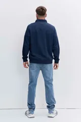 Pantalón de jean corte regular, color azul medio con efecto lavado, de tiro medio y cierre frontal con botón y cremallera.