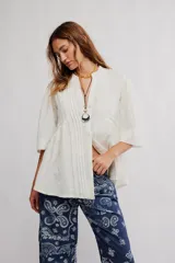 Blusa blanca con cuello mao y escote en V, de manga corta y corte amplio con fruncido frontal.