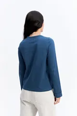 Remera de manga larga color beige, con cuello redondo y detalles calados decorativos en el borde del cuello y en los puños.