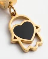 Caravanas tipo argolla con dije colgante en forma de mano de Fátima con un corazón negro en el centro, confeccionadas en acero dorado.