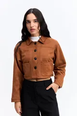 Campera corta tipo gamuza con textura suave y acabado mate. Presenta cuello camisero, cierre frontal con botones oscuros y dos bolsillos frontales de parche. Su diseño es de silueta cropped.