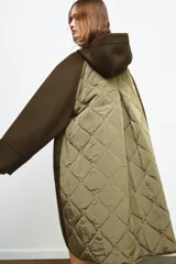 Parka oversize de corte recto confeccionada en tejido con mezcla de lana en color verde oliva. Presenta cuello alto con capucha, cierre frontal con botones y bolsillos laterales. Incluye detalles en tejido acolchado a contraste en la solapa frontal y puños.