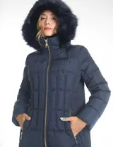 Campera puffer larga de color azul marino con capucha desmontable con borde de piel sintética. Cuenta con cierre frontal metálico dorado con logo grabado y bolsillos laterales con cierre.