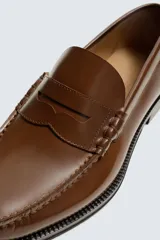 Mocasín de vestir fabricado en piel con acabado brillante, presenta detalle de antifaz en el empeine, plantilla de piel y suela a contraste con ligero tacón.
