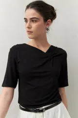 Remera blanca de manga corta con escote asimétrico y detalle de nudo con frunces en el centro del busto.