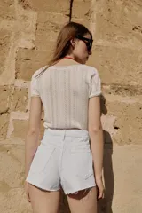 Shorts de jean tiro medio, corte mom fit, con bajo deshilachado y forro de bolsillos delanteros estampado a cuadros que asoma por debajo.