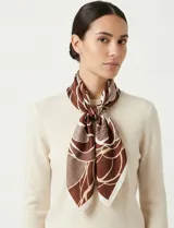 Pañuelo cuadrado de seda con estampado floral en tonos verde, blanco y negro.