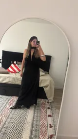 Vestido largo de terciopelo negro, con diseño al cuerpo, escote halter y pronunciado escote en V con frunce central.