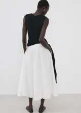 Falda midi evasé de color blanco, confeccionada en tejido de algodón con tiro medio y cintura elástica.