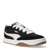 Championes Puma de estilo urbano inspirados en el skate, con perfil bajo. Presentan una estructura combinada de material sintético y superposiciones de gamuza en color negro, con el icónico logo de la marca en blanco en el lateral. Cuentan con cordones gruesos en color crema, entresuela blanca y suela de goma color caramelo.
