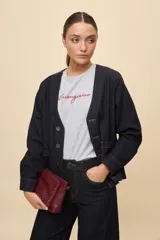 Sobrecamisa de jean azul oscuro, de calce relajado, escote en V, bolsillos delanteros aplicados, cierre frontal con botones metálicos y pespuntes en contraste.