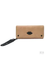 Billetera rectangular confeccionada en cuero sintético de color tostado, con un distintivo aplique central en forma de labios negros. Presenta dos tachas negras decorativas en el frente y un llavero desmontable con el nombre de la marca. Cuenta con cierre perimetral para mayor seguridad.