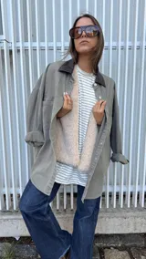 Sobrecamisa de denim en color gris con lavado desgastado, corte oversize y cuello de cuero sintético en color marrón chocolate. Cuenta con cierre frontal de botones metálicos.