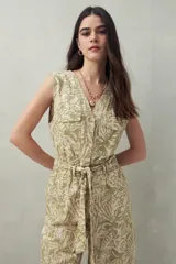 Mono largo sin mangas de algodón con estampado de hojas en tonos verde y beige. Tiene cuello en V, cierre frontal con botones, bolsillos laterales y cinturón de lazo.