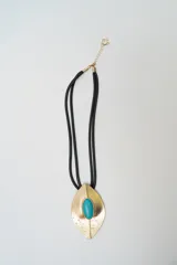 Collar de doble cordón negro con dije central de metal dorado en forma de hoja y piedra turquesa incrustada.
