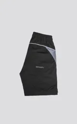 Bermuda negra de textil liviano con calce oversize, elástico y cordón de ajuste en la cintura. Presenta recortes con ribetes reflectantes grises en los bolsillos delanteros y ribetes blancos en el ruedo. Posee bolsillos traseros.