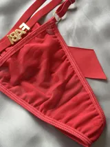 Tanga roja de tiras regulables con dije de strass con letras y gran lazo de raso al frente.