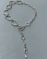 Collar de cadena con eslabones irregulares de diseño artesanal, con cierre frontal tipo barra y aro. La pieza permite diversas formas de uso, incluyendo como collar, pulsera o accesorio de espalda.