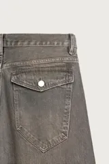 Jeans loose fit de hombre en denim de algodón color gris oscuro con efecto lavado. Presenta perneras con costuras giradas hacia los tobillos, tiro medio, cierre frontal con botones y bolsillos frontales con bolsillo cerillero.