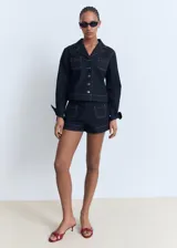 Short de tiro alto confeccionado en tejido de algodón estilo denim con costuras a contraste. Presenta diseño recto y dos bolsillos de parche en la parte delantera.