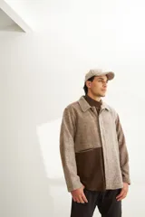 Camisa estilo leñadora con diseño patchwork en tonos marrones y beige. Presenta coderas, cartera americana y bolsillo ojal en el delantero. Confeccionada en Uruguay con tela 100% lana fina sin teñir.