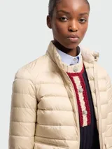 Campera corta tipo puffer de Moncler, confeccionada en nylon ligero con diseño acolchado horizontal. Presenta cuello alto, cierre frontal con cremallera, bolsillos laterales con solapa y ajuste elástico en los puños.
