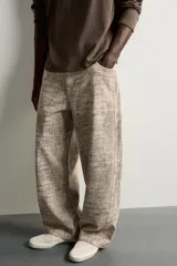 Pantalón relaxed fit de algodón con estampado animal print de cocodrilo en tonos beige y gris. Tiene diseño de cinco bolsillos, cierre frontal con cremallera y botón, y una tira con bolsillo multifunción en la pernera.