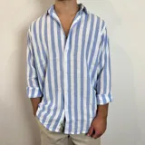 Camisa celeste y blanca a rayas verticales, de corte recto y mangas largas con puños abotonados.
