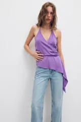 Top de satén color lila con escote en pico cruzado, tirantes finos ajustables y bajo asimétrico con caída lateral.