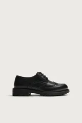 Zapato de vestir tipo brogue negro, con detalles de perforaciones decorativas y suela track dentada.