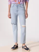 Jeans recto de tiro medio, color celeste claro, con roturas en las rodillas.