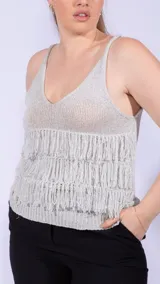 Top de tejido de punto color dorado brillante, con escote en V y tirantes finos. Presenta tres hileras horizontales de flecos largos en la parte delantera.