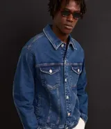 Campera trucker de jean azul oscuro, con cuello tradicional, cierre frontal con botones, cuatro bolsillos y mangas largas.