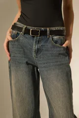 Pantalon jean de corte recto y tiro medio, con un lavado desgastado y un dobladillo ancho en la parte inferior que deja ver el revés de la tela con costuras en contraste.