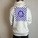 Canguro blanco con capucha y estampado en la espalda de un tablero de ajedrez violeta con una cara sonriente distorsionada y la frase "Good Vibes".