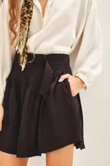 Short negro de tiro alto con pliegues y cinturón con hebilla metálica. El tejido presenta un sutil estampado jacquard.