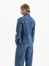 Camisa de denim con lavado clásico, corte entallado en la cintura y silueta evasé hacia el ruedo. Presenta cuello camisero, cierre frontal con botones metálicos y dos bolsillos con solapa en el pecho.