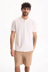 Chomba de piqué color blanco, con cuello polo y cierre frontal con tres botones.