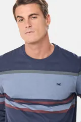 Remera de manga larga con diseño de rayas horizontales en tonos azules, grises y bordó. Presenta cuello redondo y un pequeño logo bordado en el pecho.