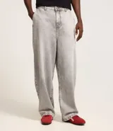 Pantalón de jean corte baggy, de tiro alto y pierna ancha, con diseño de cinco bolsillos, trabillas para cinturón y cierre frontal con botón y cremallera.