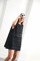 Vestido corto sin mangas, de tejido de punto en color azul marino con efecto jaspeado o tweed en tonos claros. Presenta un corte amplio y relajado, con cuello redondo y bordes en contraste.