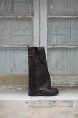 Bota de cuero marrón con diseño 2 en 1, que permite usarla con o sin polaina. Presenta una suela track robusta, cierre lateral y una tira con hebilla metálica en la parte superior de la caña.