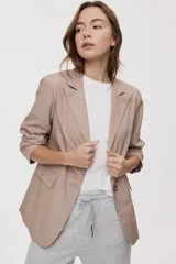 Blazer sastrero color tostado de calce relajado, con solapa clásica, cierre de un botón, bolsillos con tapa y mangas largas.