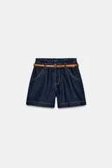 Bermuda baggy de denim azul oscuro, de tiro alto con cintura paperbag elástica y cinturón marrón incluido. Presenta bolsillos delanteros, costuras contrastantes en tono tostado y cierre frontal con cremallera y botón.