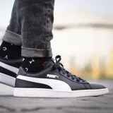Championes Puma modelo Smash V2 L, de diseño clásico y minimalista en color blanco con la icónica franja lateral en negro. Confeccionados con materiales sintéticos de alta calidad, cuentan con suela de goma resistente y cierre de cordones para un ajuste seguro.